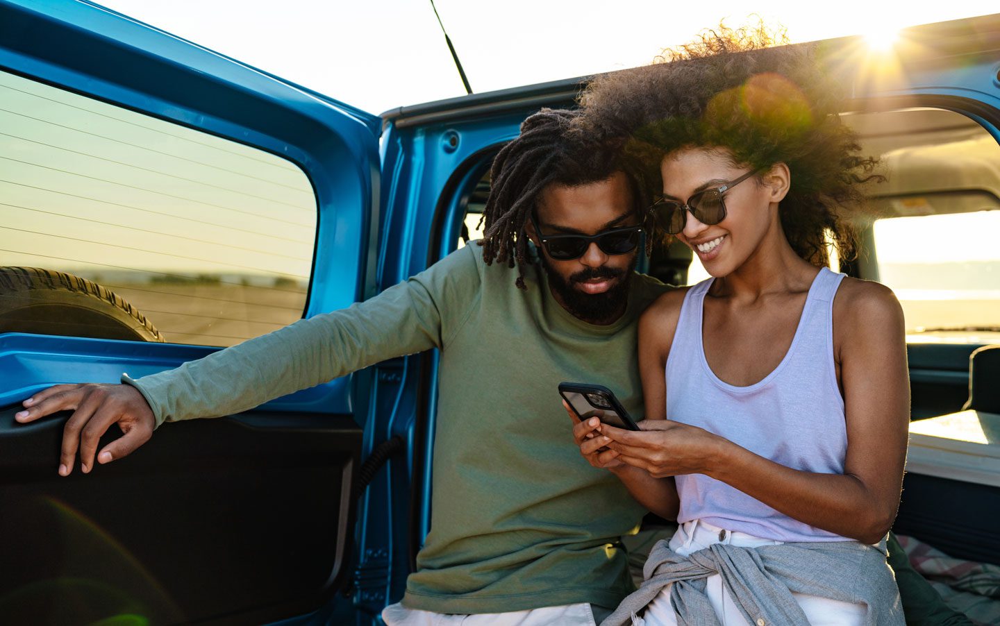 Two people in a blue 4x4 looking at a mobile